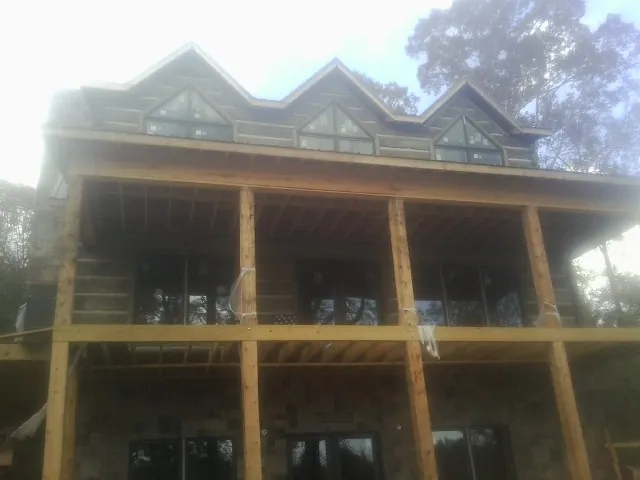 Dormers and porch framing on a large log home under construction — Roof Coating work by our crew in Oneida