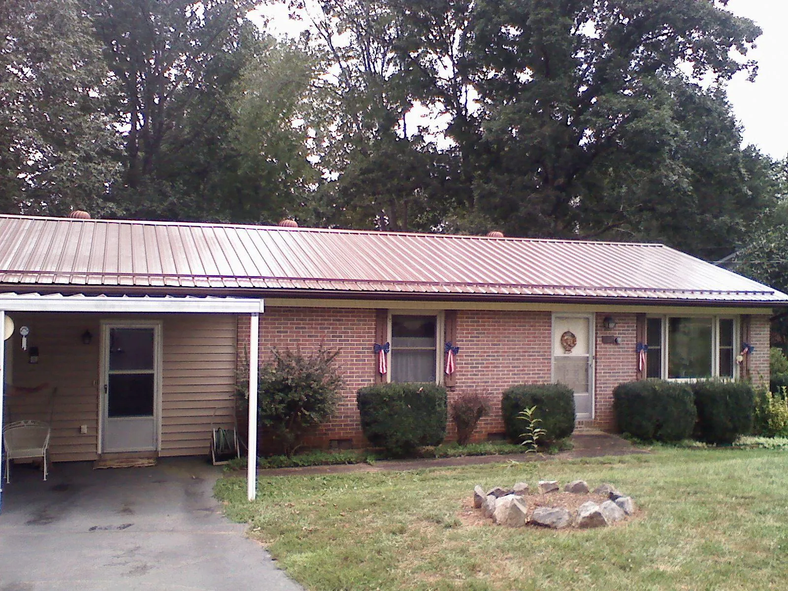 Bronze metal roof and carport on a brick ranch home — Roof Repair work by our crew in Oneida
